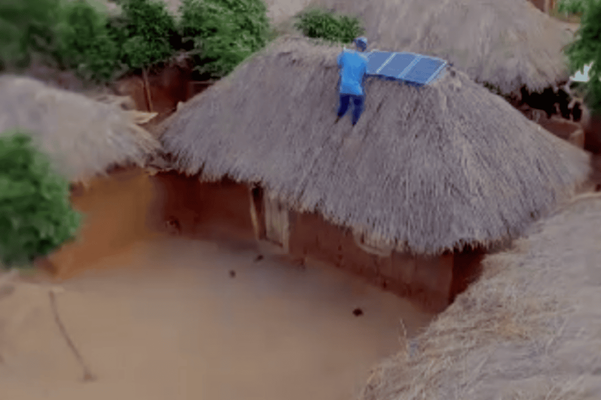 Man Putting Solar Panels On Mud Hut