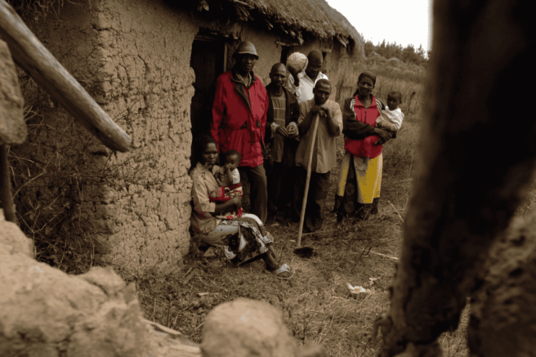Group Of People Standing By Mud Hut